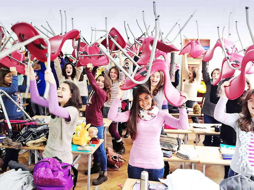 Laughing pupils in classroom with chairs